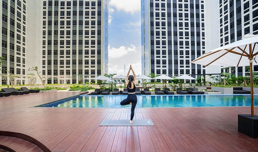 Woman doing yoga on the deck by the pool at LK Cikarang Hotel & Residences