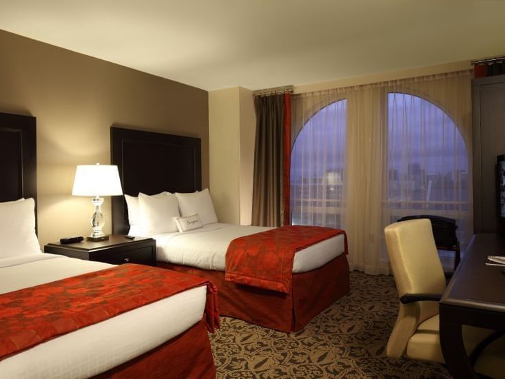 two double beds in carpeted hotel room with window