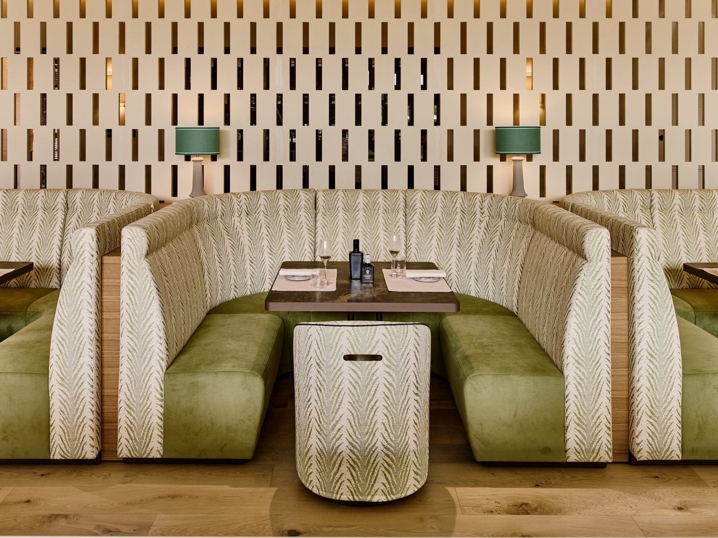 Elegante Sitznischen mit olivgrünen Polstern und gemusterten Rückenlehnen im HOKU Restaurant & Lounge im Falkensteiner Resort Lake Garda.