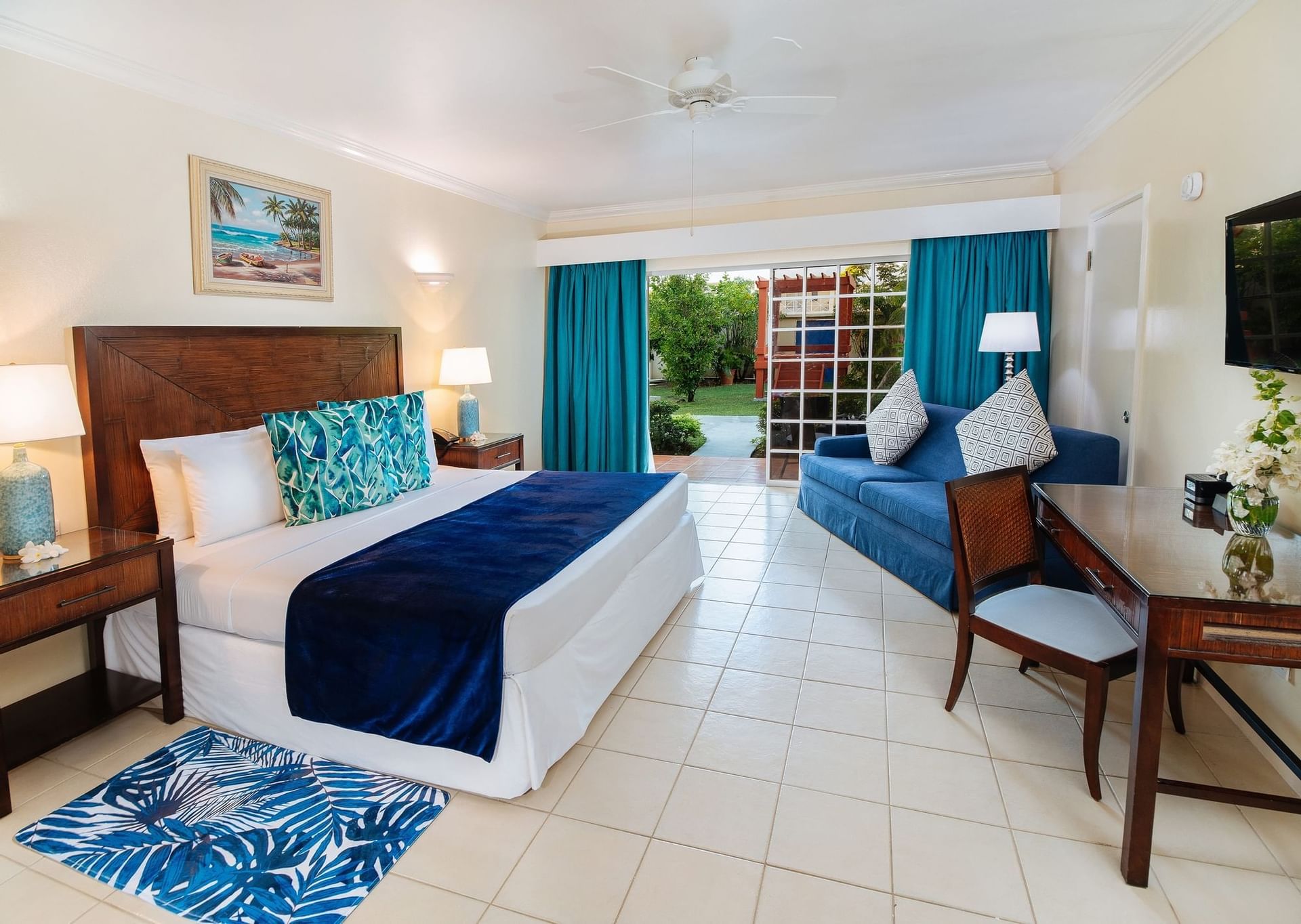 Seating area, work desk, and TV by the cozy bed in Jr Executive Suites at Bay Gardens Hotel