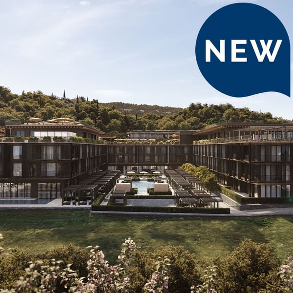 Neues Hotel mit Pool, umgeben von Gärten und bewaldeten Hügeln im Hintergrund.