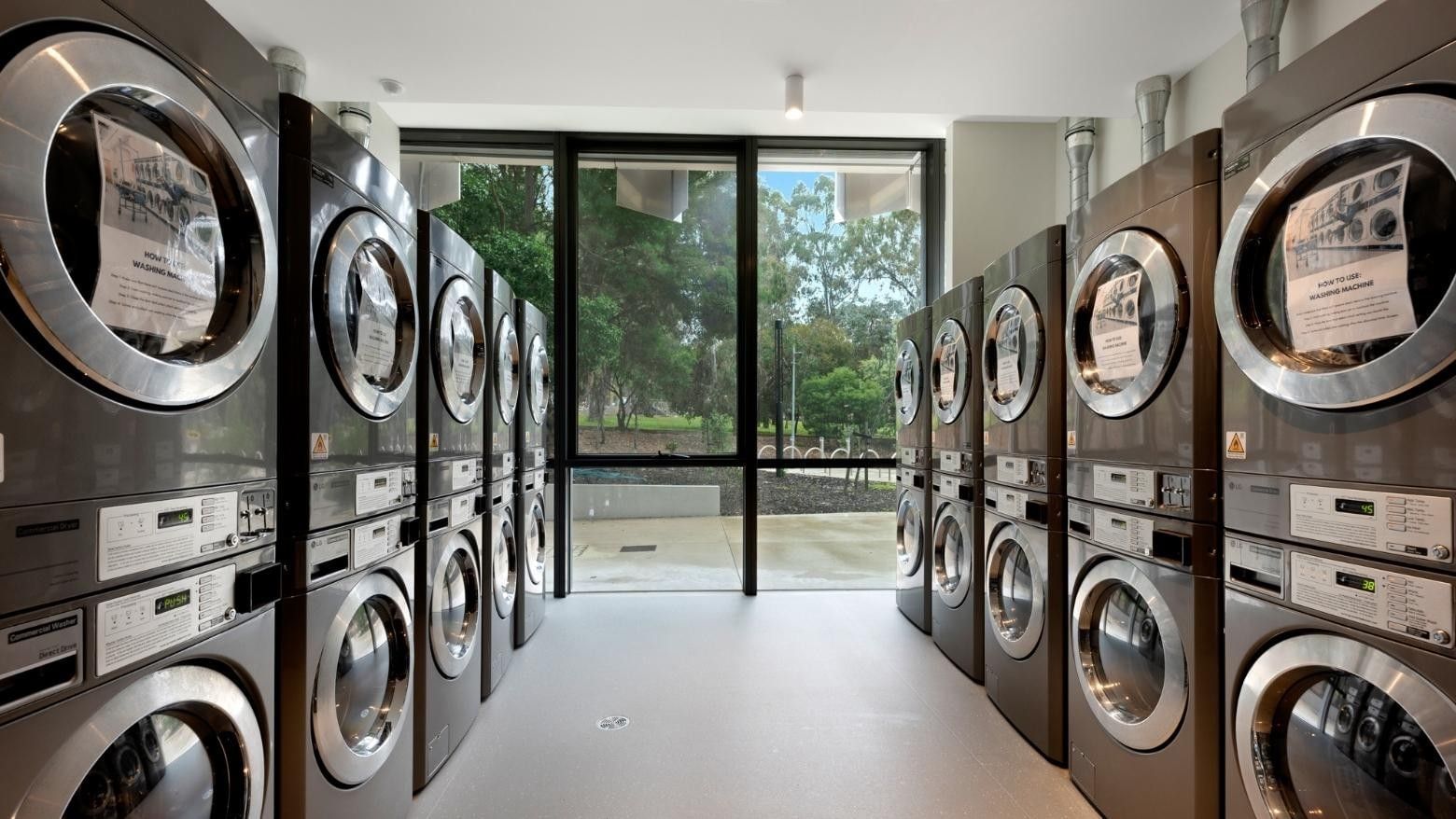 Row of washing machines and dryers in a clean, modern laundry room.