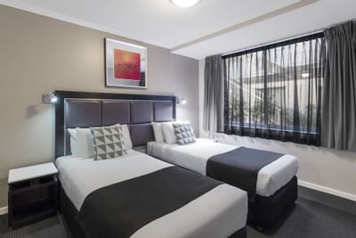 Twin beds with black linen in a room at Nesuto Hotels