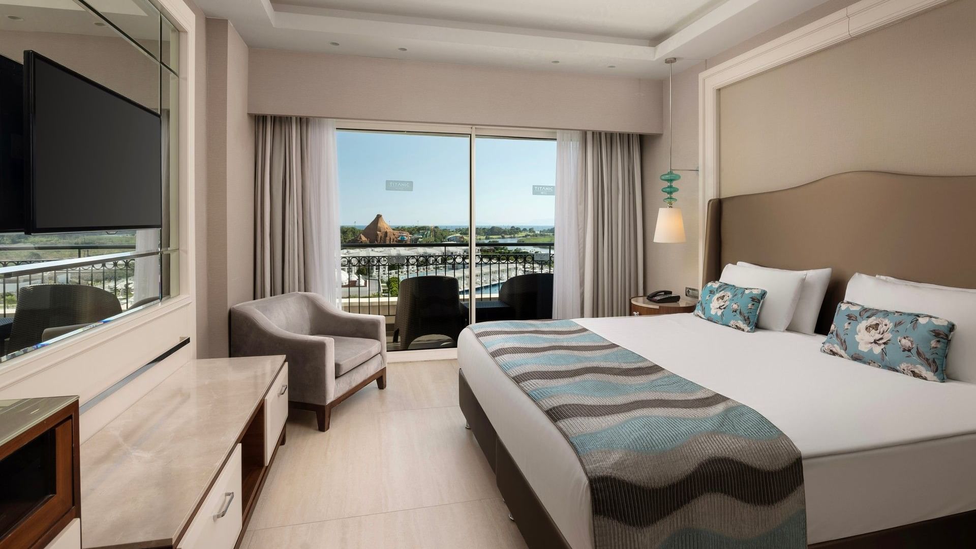 Geniş yatak, oturma alanı ve balkon manzaralı modern süit oda,  Titanic Deluxe Golf Belek'te