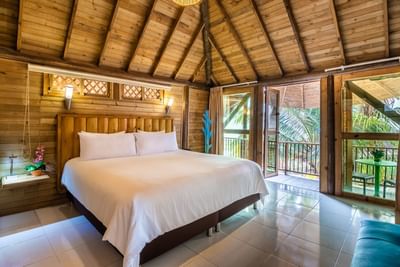A cozy bed and warm wooden walls with balcony in Bungalow at Hotel Isla Del Encanto