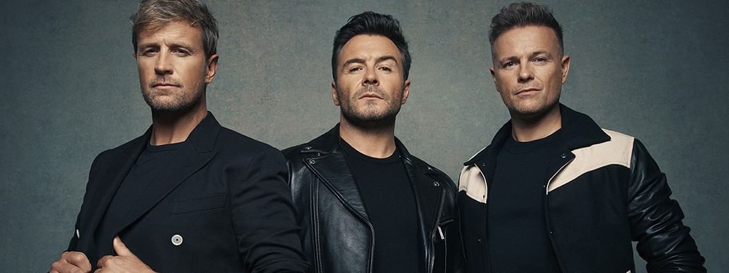 Three Westlife members pose together for a photo advertising the Anniversary World Tour 2027.