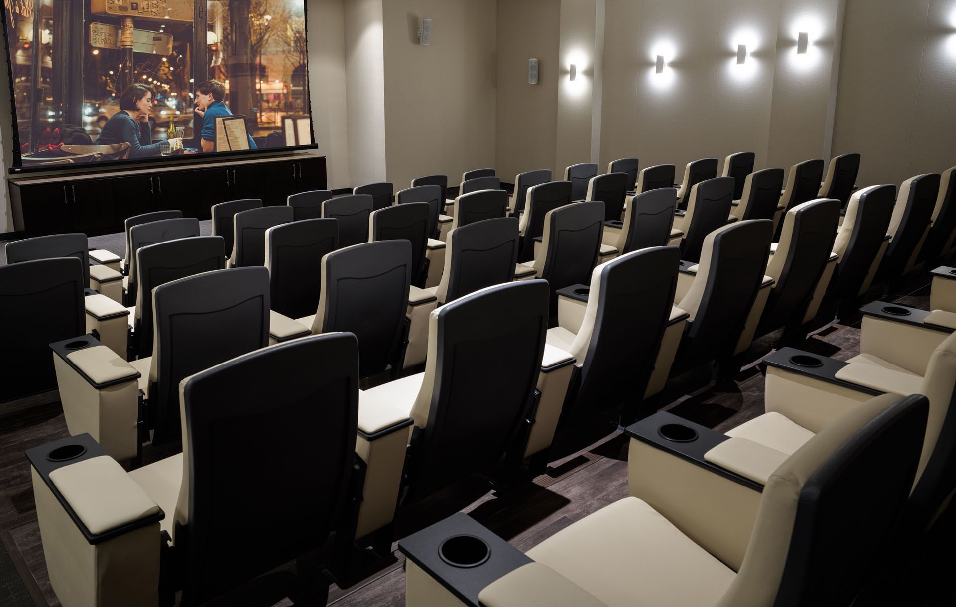 Private cinema hall with beige and black plush seats facing a large active movie screen inside Hotel X Toronto