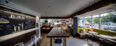 Long metal table with white stools near counter in J House Coffee Bar at The J House Greenwich