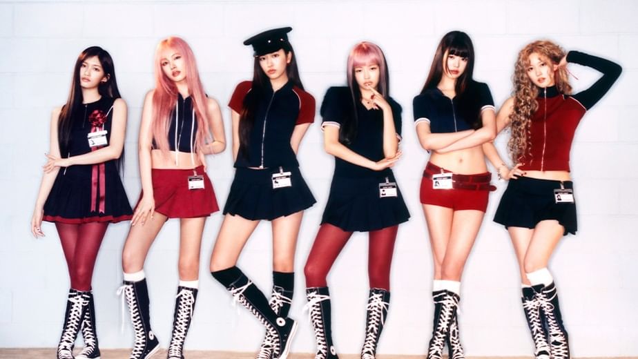 Six women in matching outfits posing for the camera in front of a white wall.