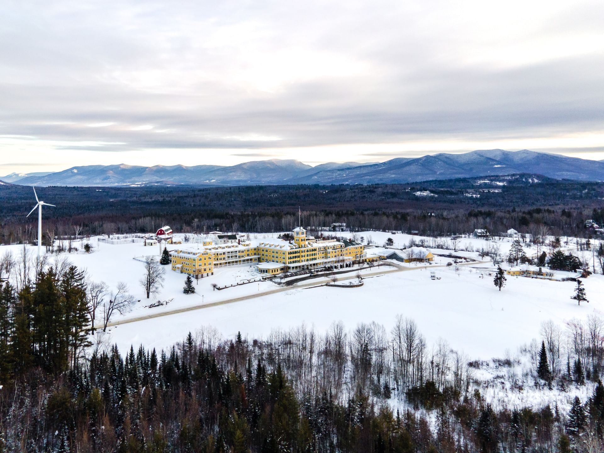 High aerial view of snow-covered grounds surrounding Mountain View Grand Resort & Spa with mountains in the distance
