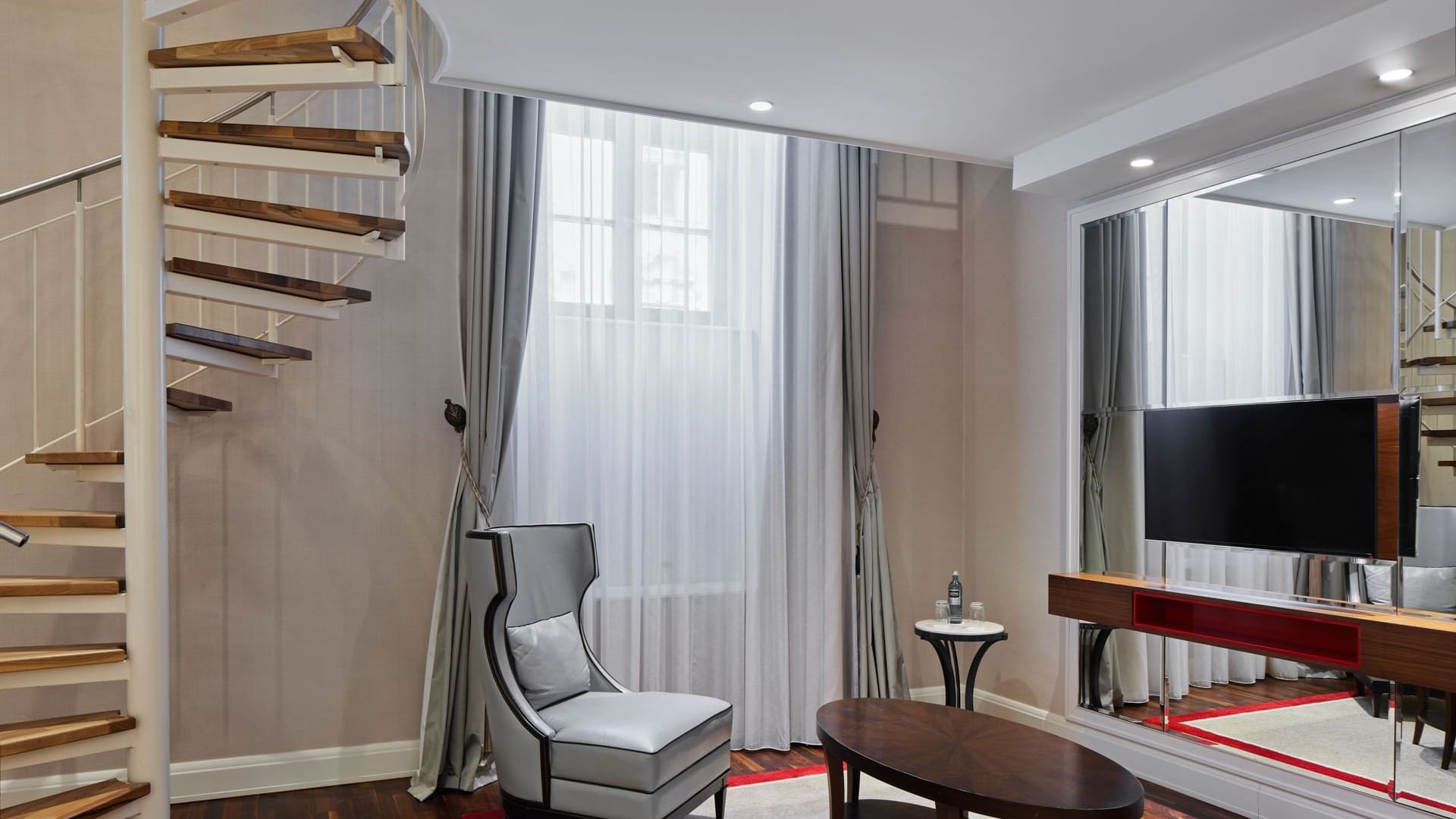 TV lounge area with spiral staircase in Gendarmenmarkt Duplex Suite at Titanic Gendarmenmarkt Berlin