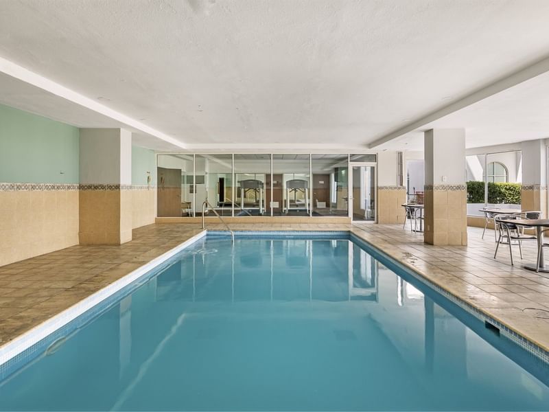 Piscina interior larga en Fiesta Inn Express Nuevo Laredo con agua azul y paredes beige y verdes