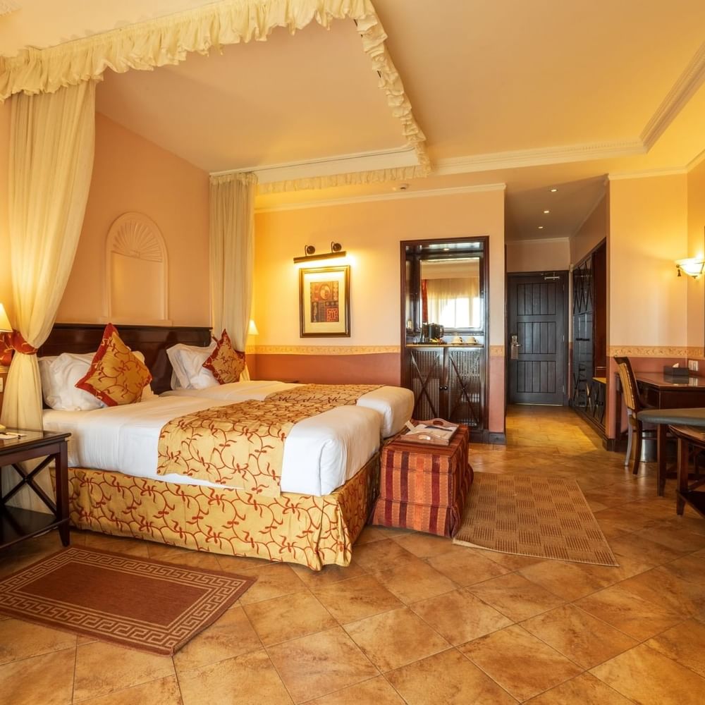 Standard Twin Room with two beds, warm decor, and elegant furniture at Lake Victoria Serena Golf Resort & Spa in Kampala.