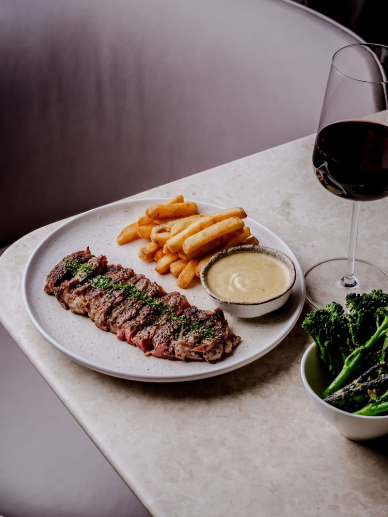 Steak, fries, sauce, and wine on a table at The May Fair Hotel, London.