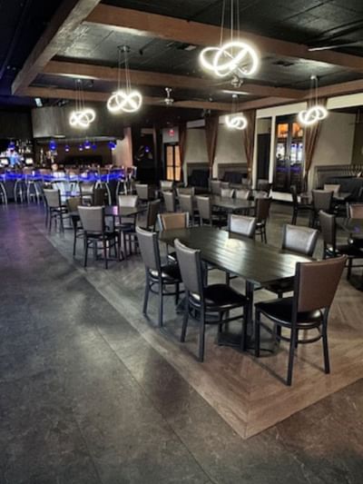 Modern dining area with wooden tables, upholstered chairs, and contemporary pendant lighting at London Bridge Resort