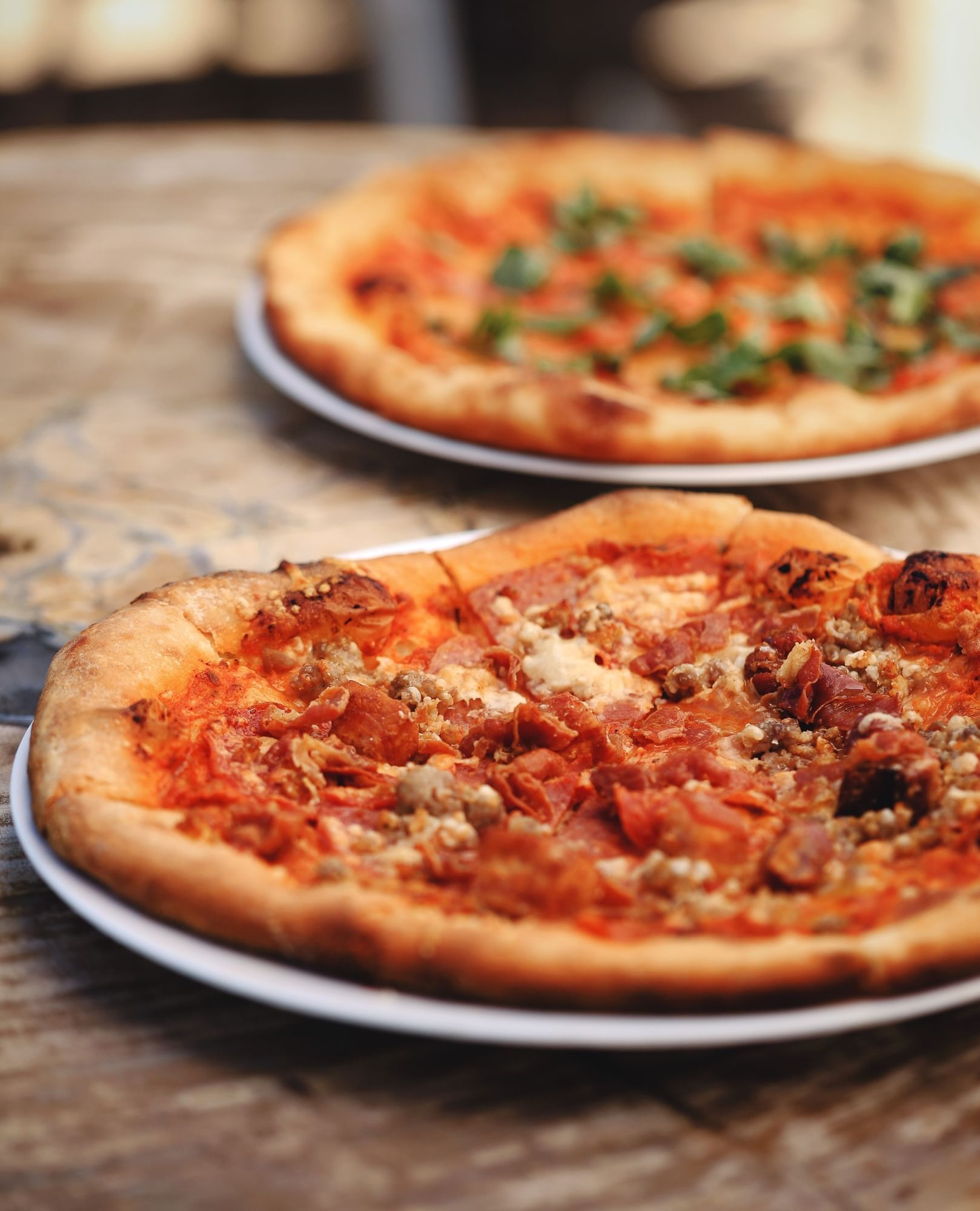 Lorem ipsum Two pizzas. One with red sauce, pepperoni and sasage. The other in back with tomatoes and basil