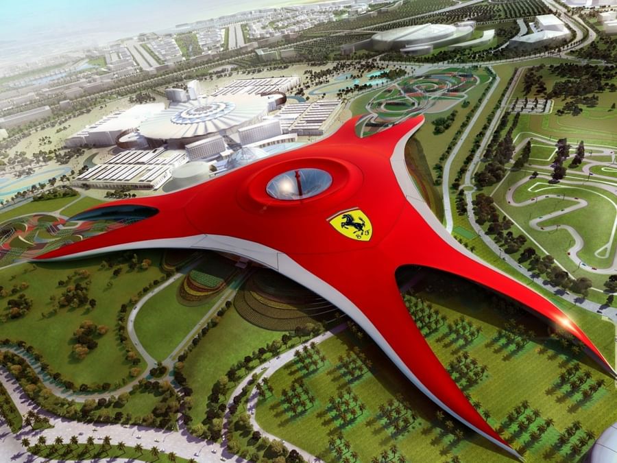 Aerial view of Ferrari World in Abu Dhabi with a central emblem, surrounded by greenery near DAMAC Hotels & Resorts