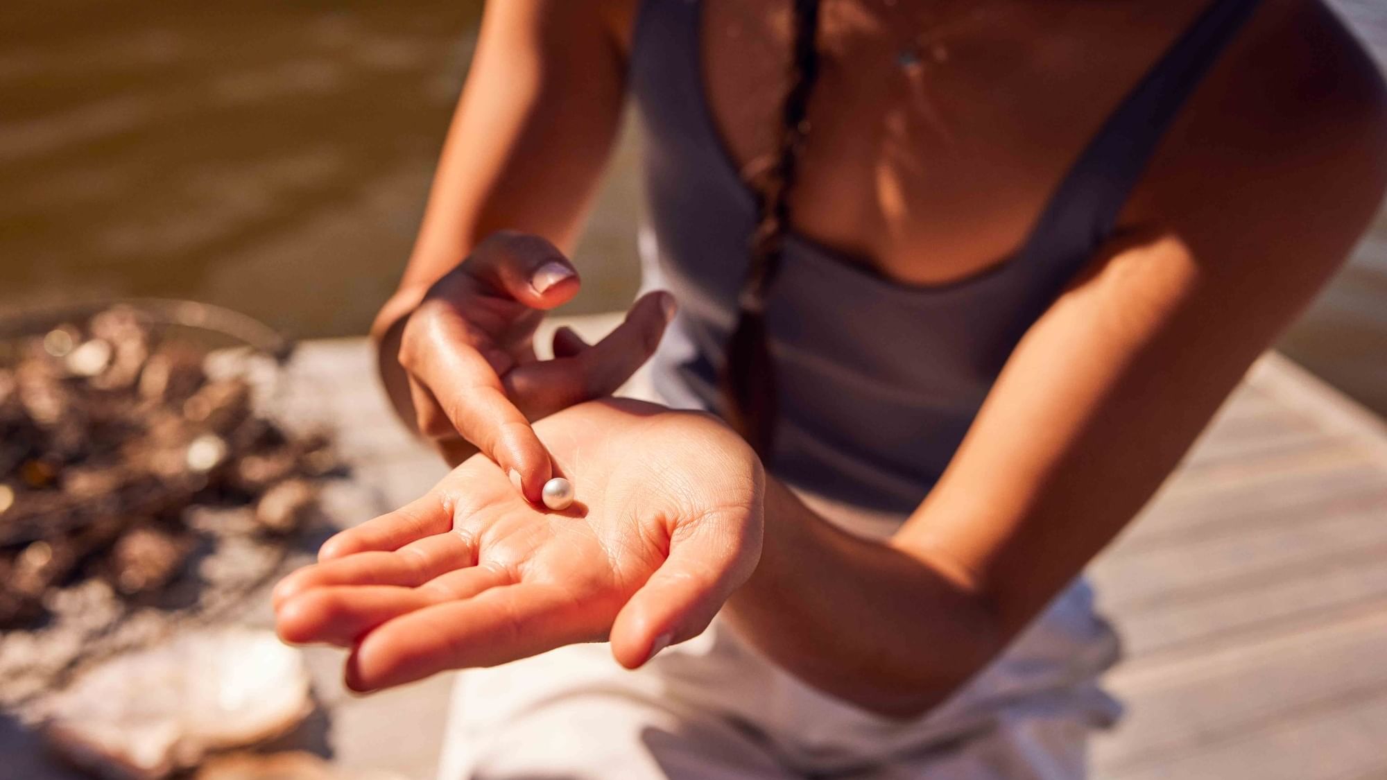 Women holding a pearl on dock at Broken Bay near Pullman Magenta Shores
