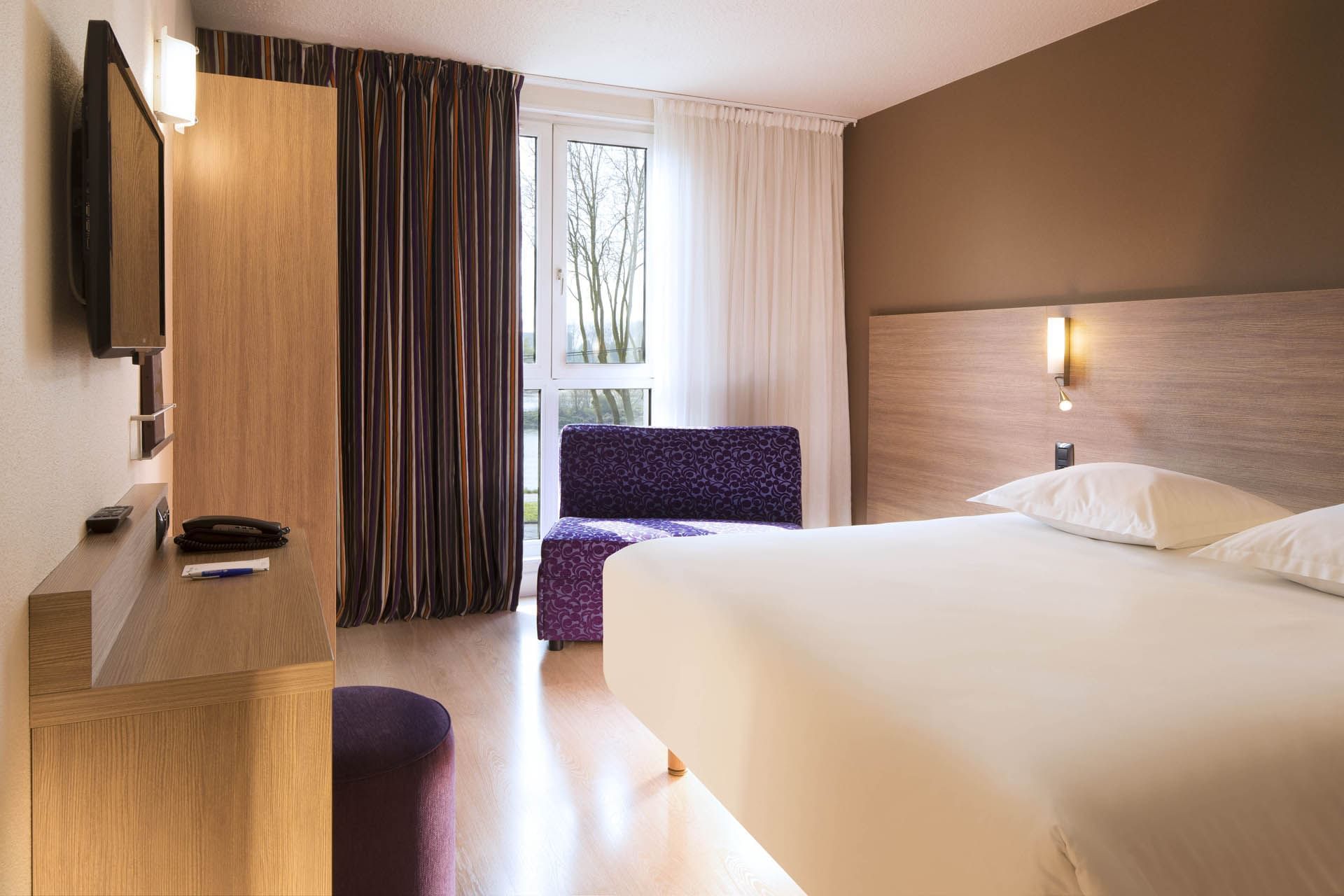 Lit king et salon dans une chambre à Escale Oceania Orléans