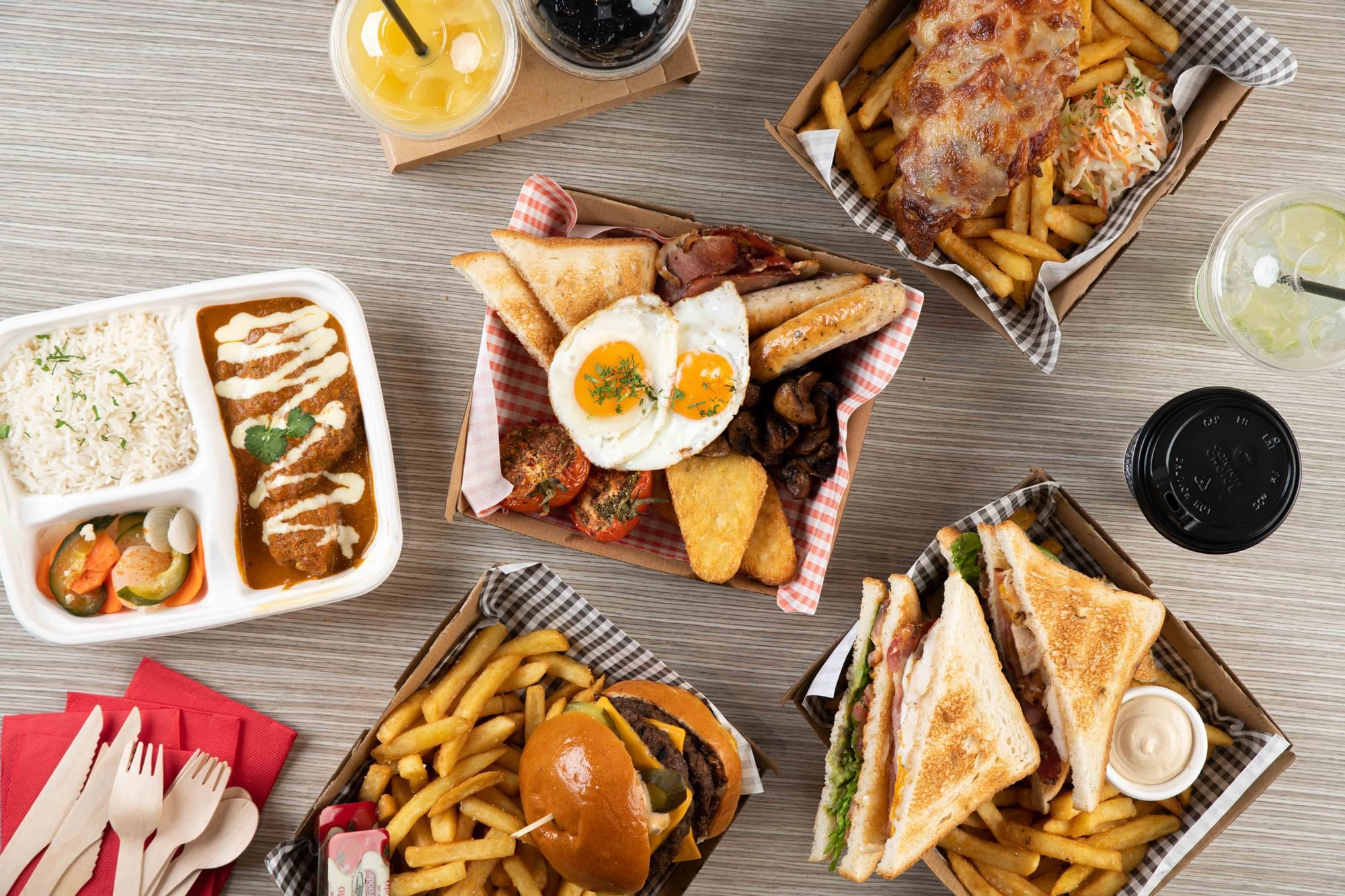 Delicious spread of burgers, curry with rice, fries, and drinks served on a table at Ibis Adelaide
