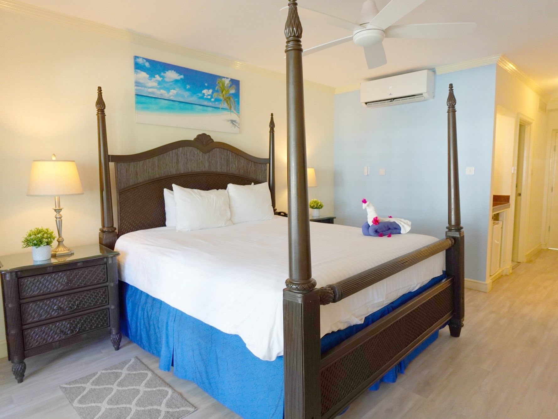 Family Suite with four-poster bed, white linens, blue accents, and beach artwork at Savannah Beach Hotel, Bridgetown.