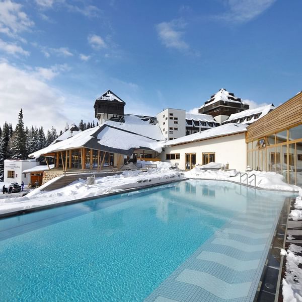 Outdoor pool with hotel exterior at Falkensteiner Hotels