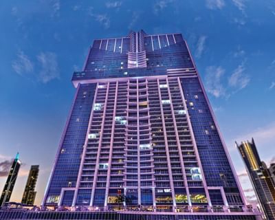 Exterior view of Megapolis Hotel Panama, a purple-lit high-rise tower against the dusk sky near the city skyline