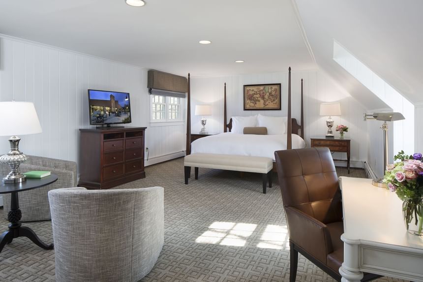 Spacious guest room with four-poster bed, seating area, TV, and natural light at Aramark Chauncey Conference Center