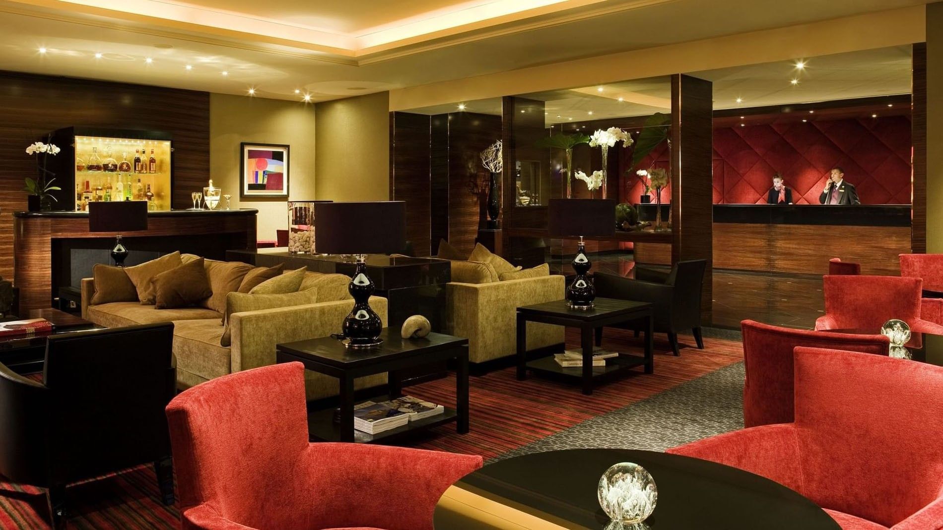 A luxurious hotel lobby with a seating area, bar, and reception desk.