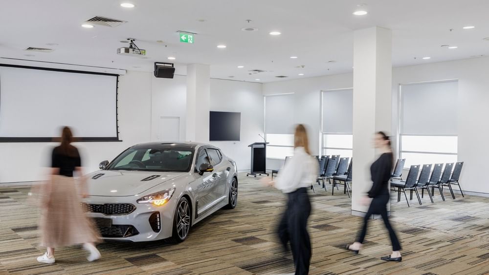 Silver car on display in the Parklands Room with people at Novotel Sydney Olympic Park