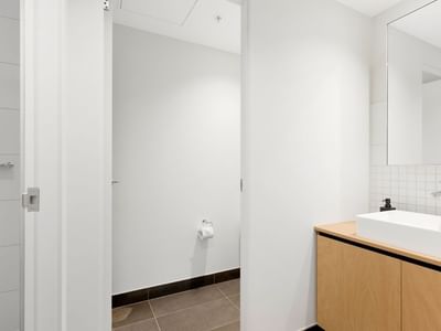 Clean bathroom with white sink, mirror, and wooden cabinet in La Trobe University apartments.