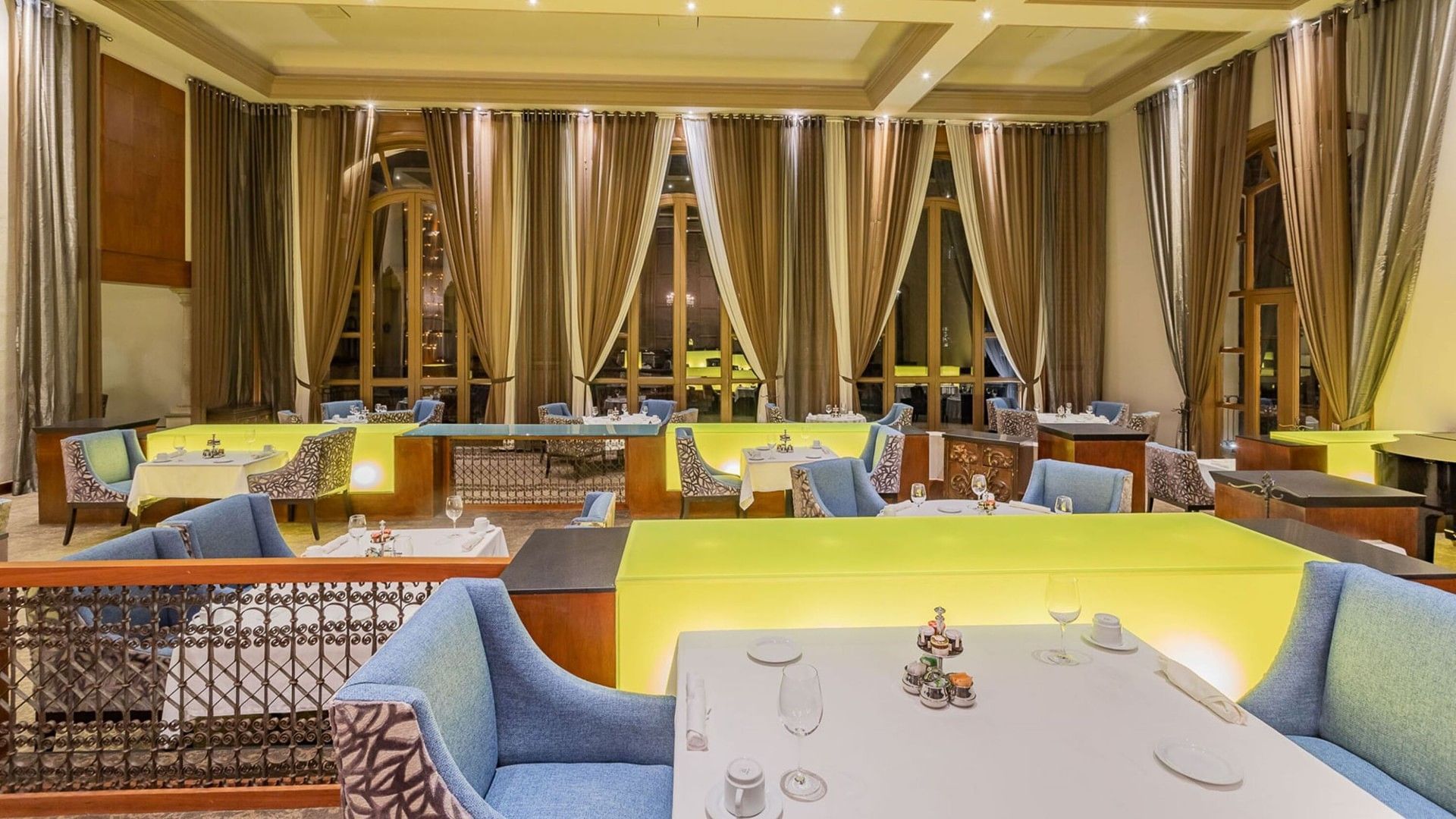 Tierra Mía restaurant with glowing yellow partitions, chandeliers, and white table cloths at Quinta Real Monterrey