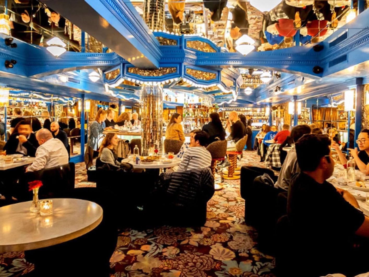 Piano Piano restaurant with patrons dining, chandeliers, and blue ceiling beams near Hotel X Toronto