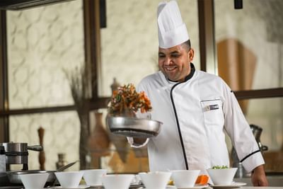 Chef smiling and making a dish in uhud at Elaf Al Taqwa Hotel