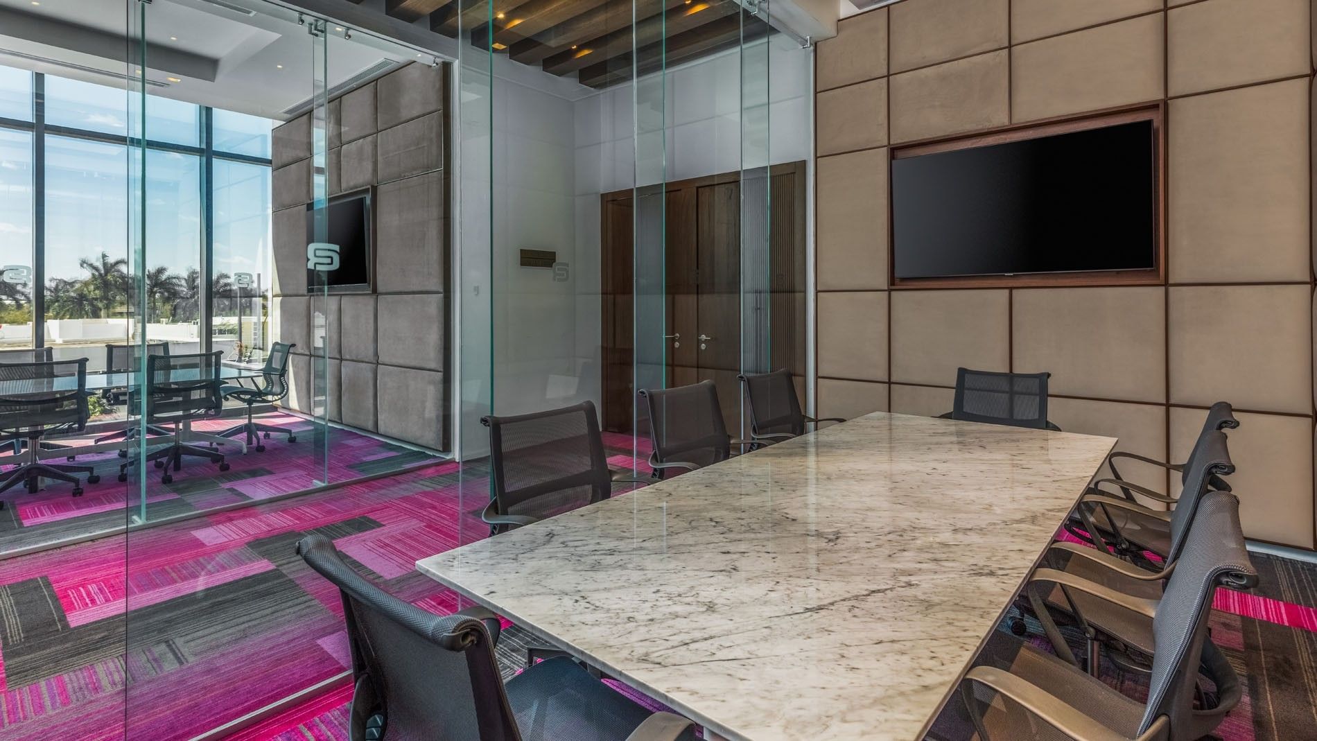 Professional boardroom featuring a marble table, purple carpet, and glass partitions at Camino Real Merida