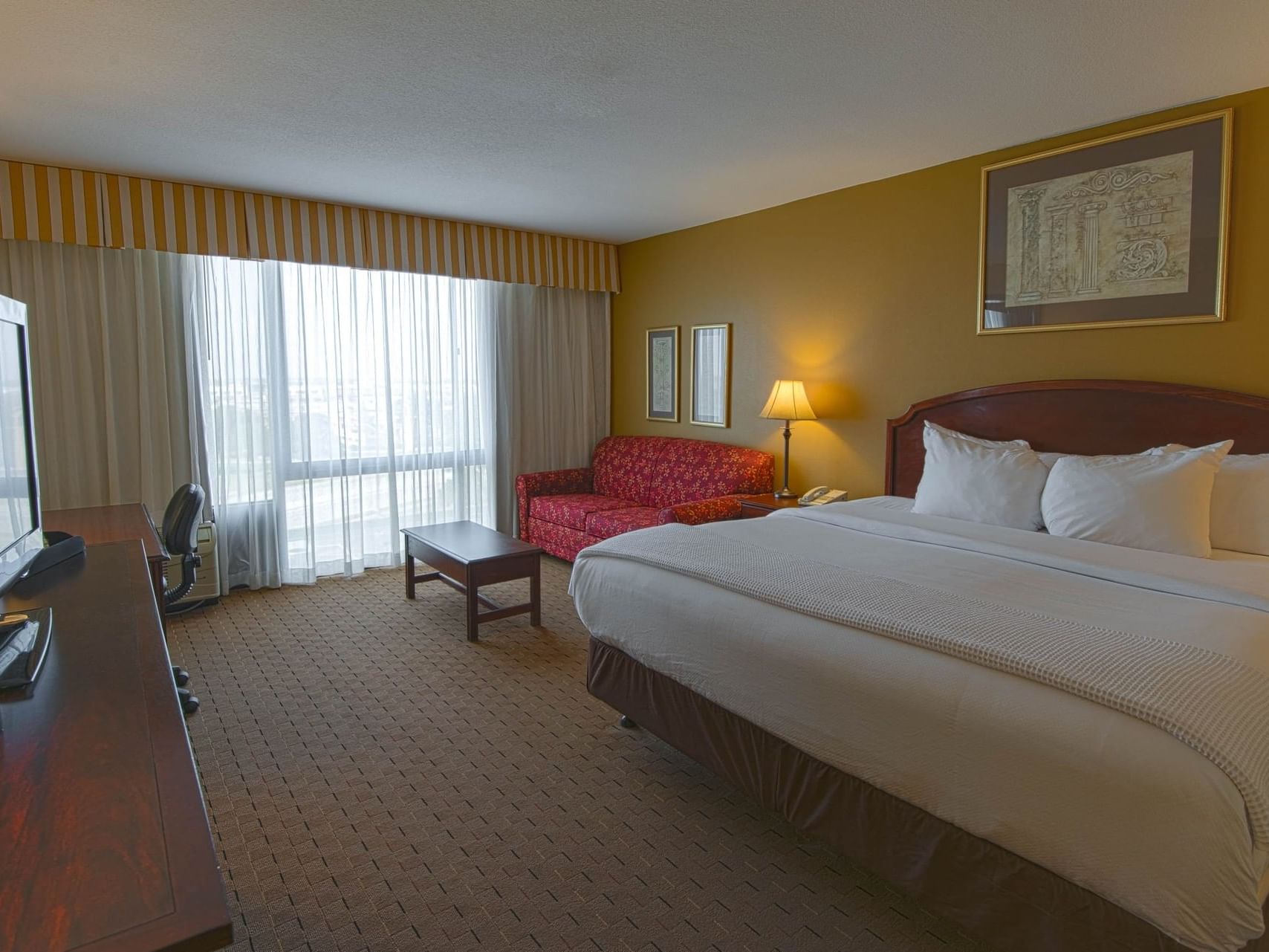 Couch by a comfy bed in Standard King Room at MCM Hotel Lubbock