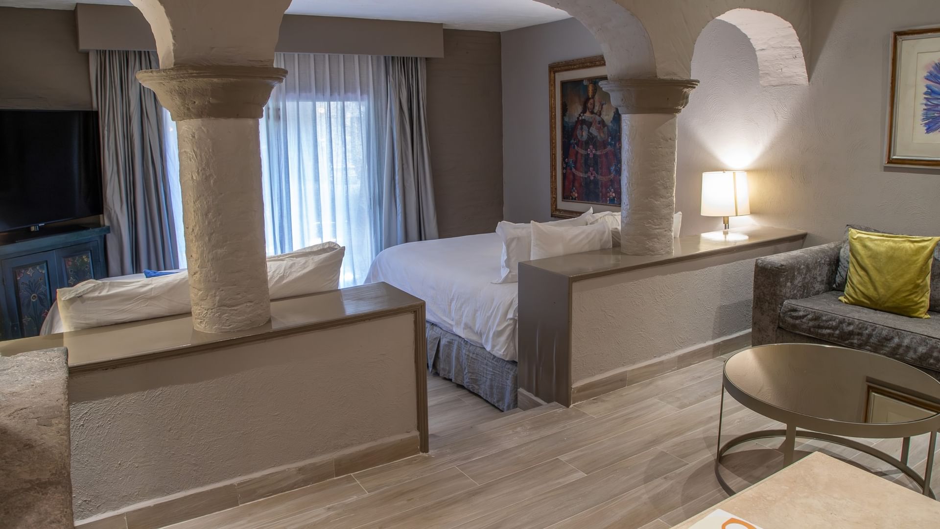 Master Suite con dos camas dobles, columnas de piedra, arcos decorativos y área de estar en Quinta Real Guadalajara