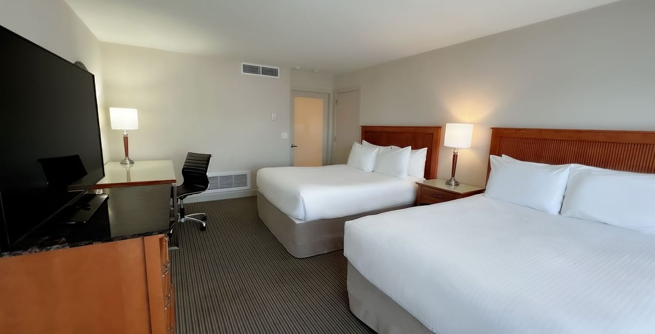 Hotel room with two queen beds, work desk, chair, and TV