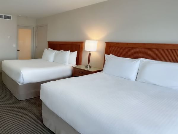 Guest room with two queen beds, desk, chair, tv, lamps