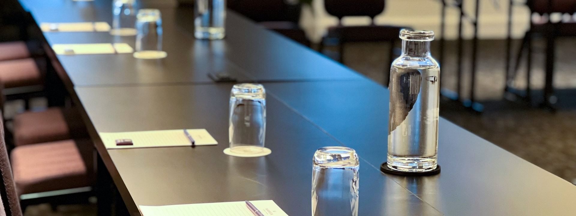 Tables set with glass water bottles by chairs near windows in Salon Crescent at Warwick Le Crystal Montreal