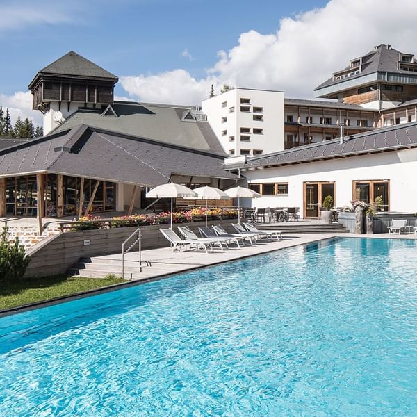 Pool & hotel exterior view on a sunny day at Falkensteiner Hotels & Residences