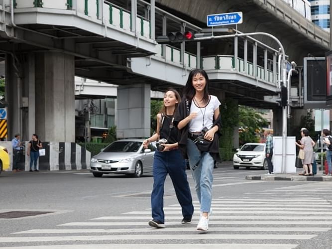 Two women crossing a road near Maitria Hotels & Residences