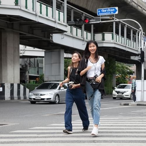 Two women crossing a road near the Chatrium Residence Sathon