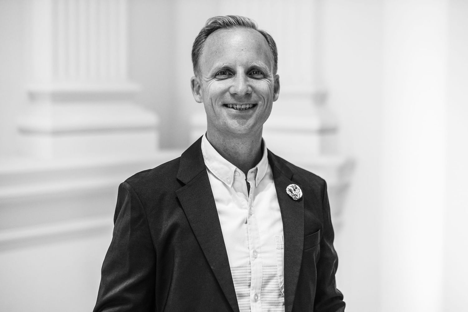 Man in a suit with a lapel pin at Almanac Group