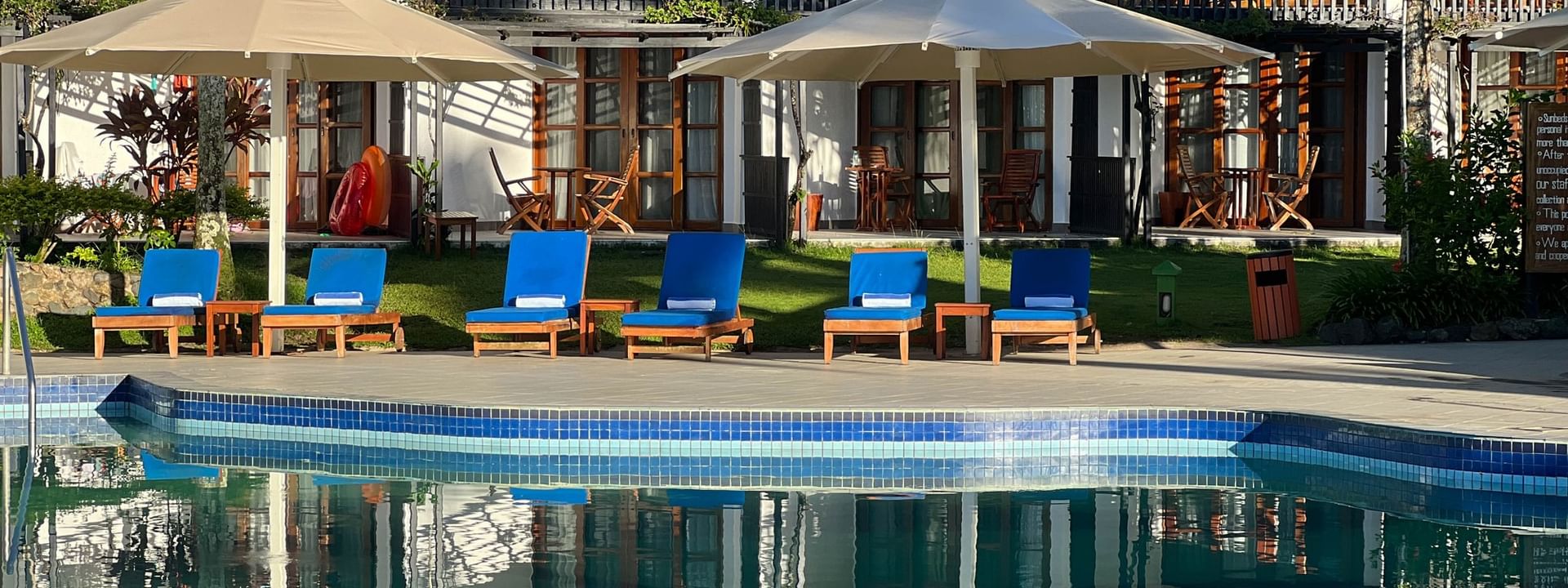 Blue lounge chairs by a poolside under large white umbrellas at Warwick Fiji Resort and Spa in Korolevu