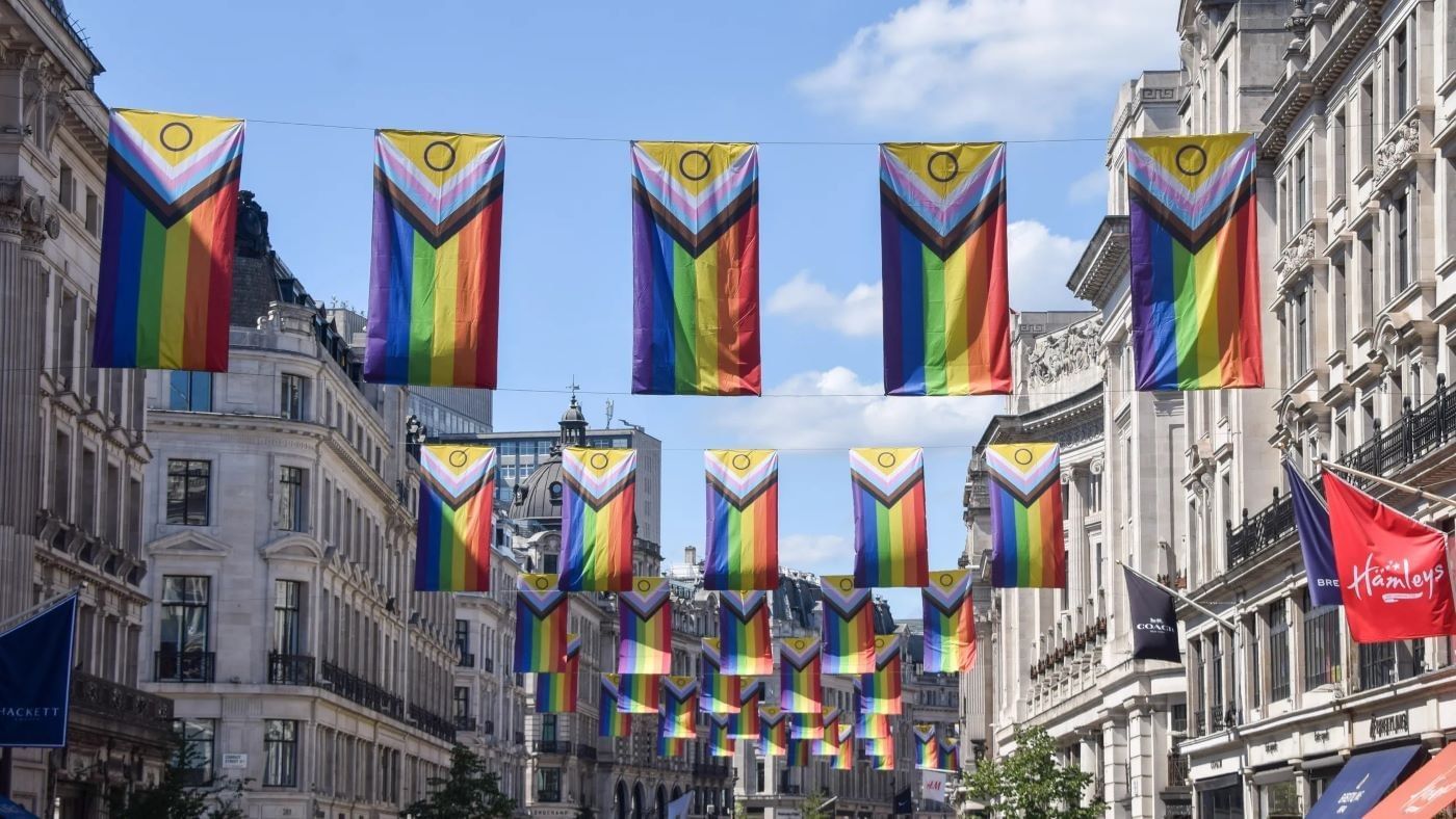 Vibrant progress pride flags hanging across a busy street for Pride in London, located near The Londoner Hotel
