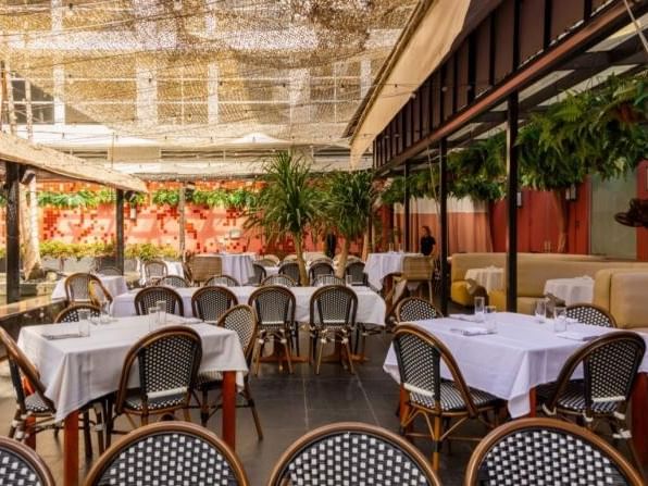 Orange Blossom with white tablecloths, woven wicker chairs, and a shade cover at The Plymouth Hotel South Beach