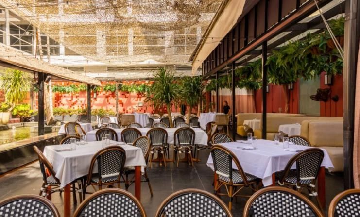A restaurant patio with white tablecloths and wicker chairs.