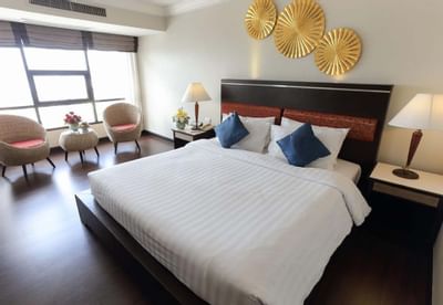 Large bed & chairs by the window, Bedroom at Amora Hotel