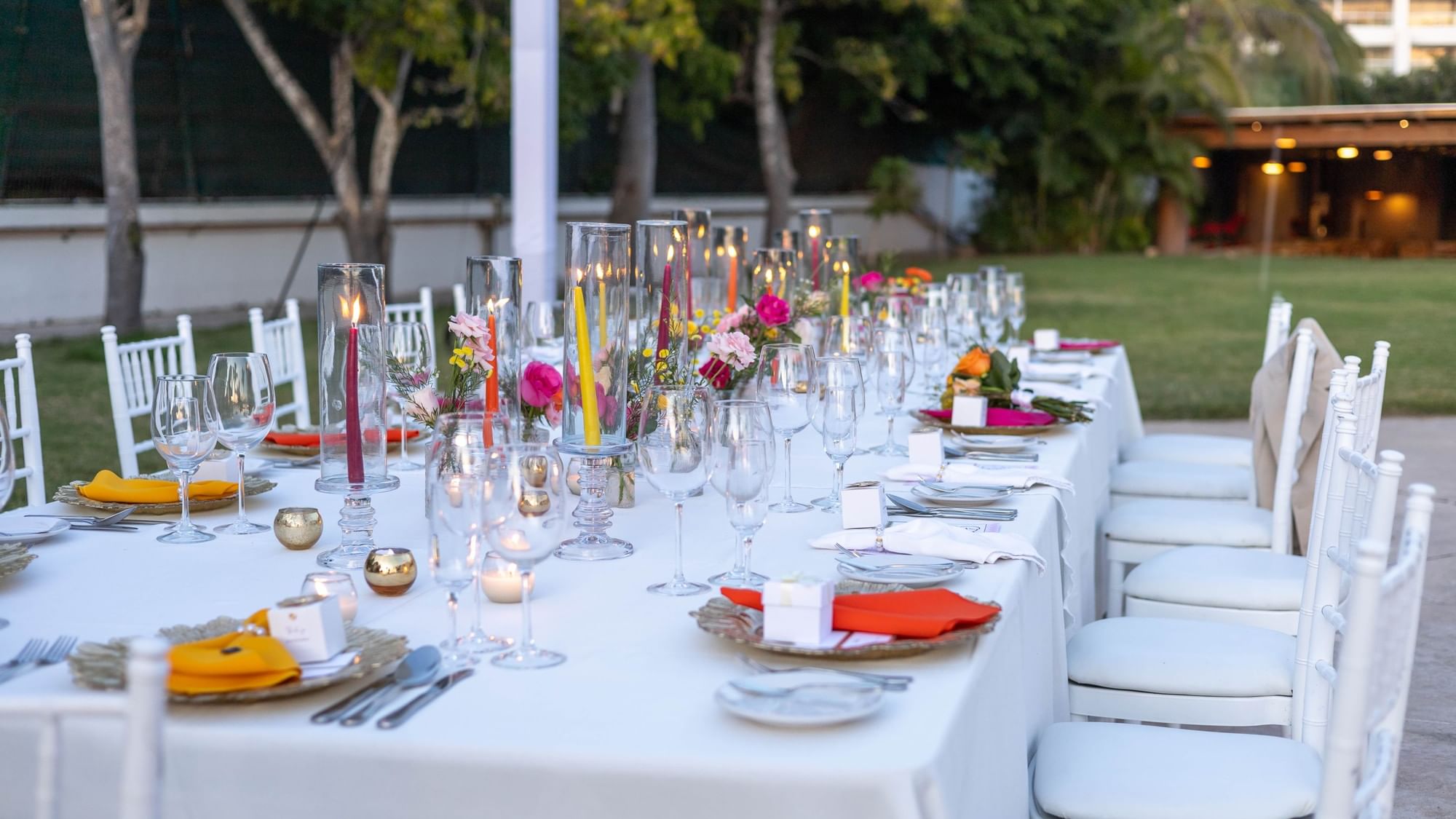 Long outdoor table with elegant decor and lit candles set in tropical surroundings at Fiesta Americana Riviera Nayarit Resort & Spa.